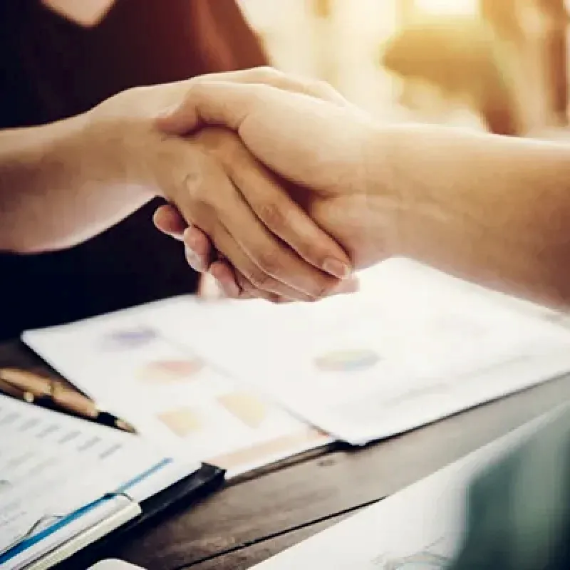 primer-plano-de-dos-personas-de-negocios-dandose-la-mano-mientras-esta-sentado-en-el-lugar-de-trabajop